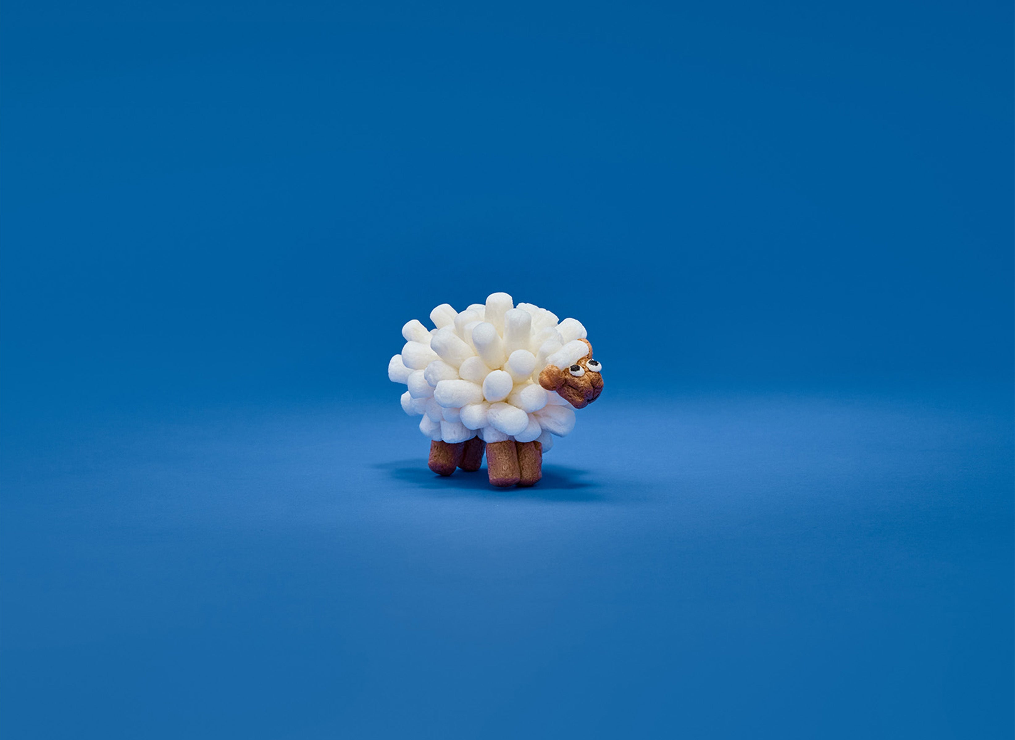 Eine Schafskulptur aus weißen Nubsis auf einem blauen Hintergrund.