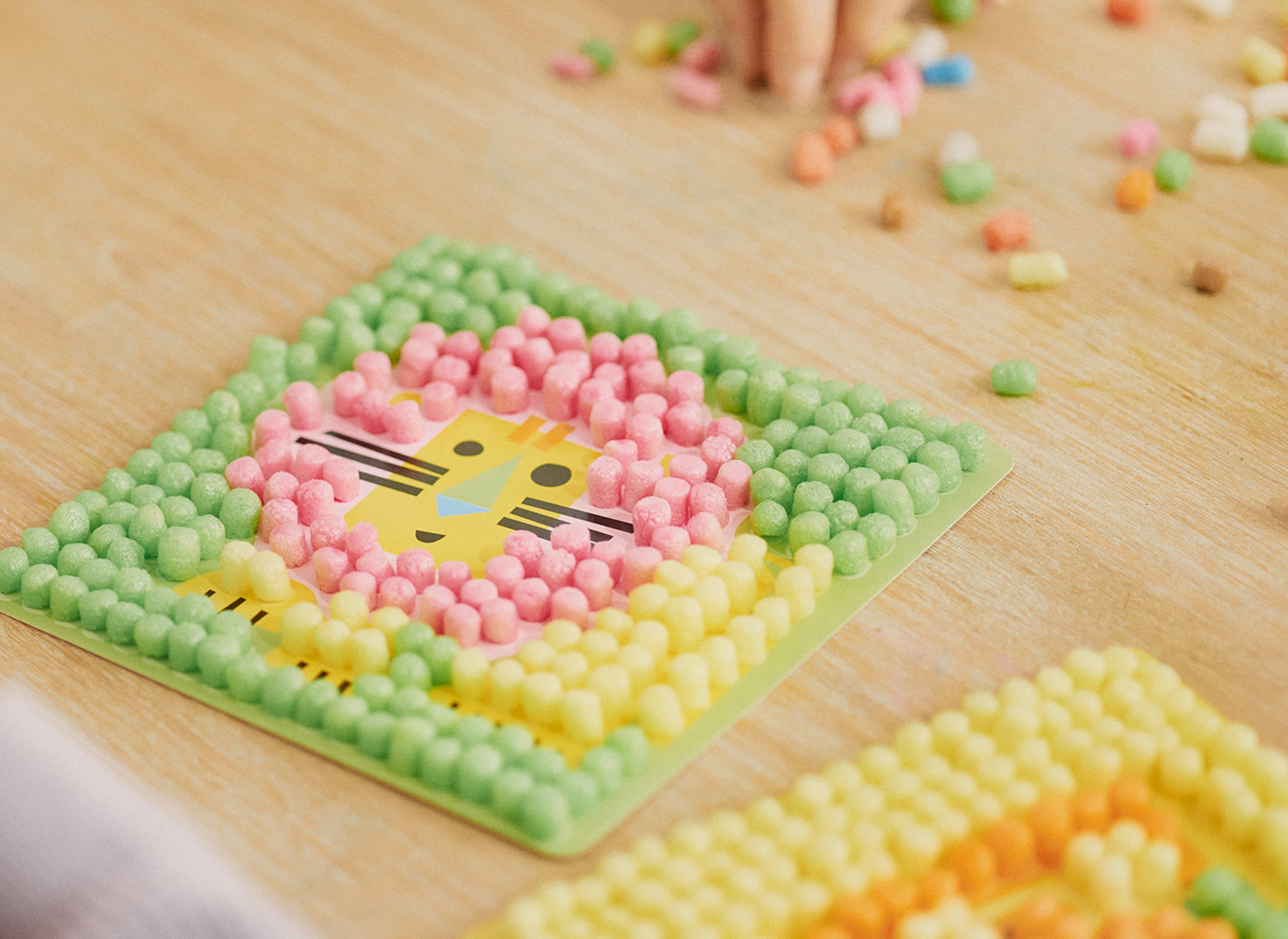 Bunte Nubsis formen ein Bild auf einer Karte mit einem Löwengesicht, auf einem Holztisch verteilt.