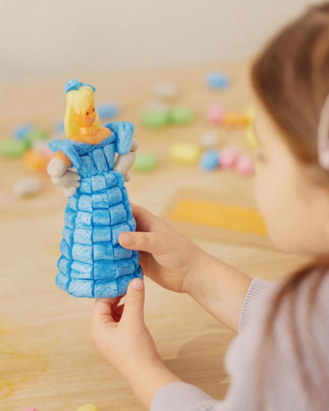 Ein Kind hält eine Figur aus blauen Nubsis in Form einer Prinzessin mit gelbem Haar.
