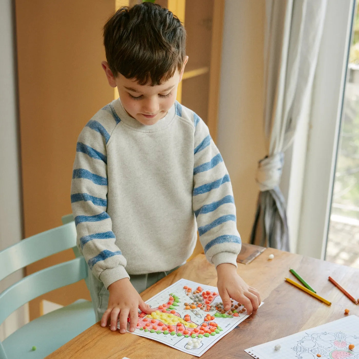 Kind beklebt Motive des Eduline Mosaic Activity Books.