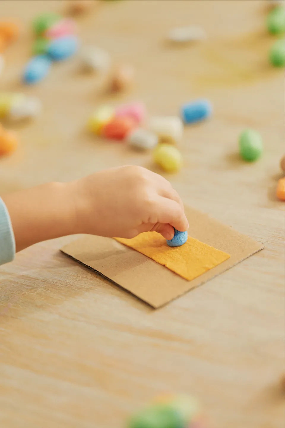 Eine Kinderhand feuchtet ein Playmais-Teil am Schwamm an.