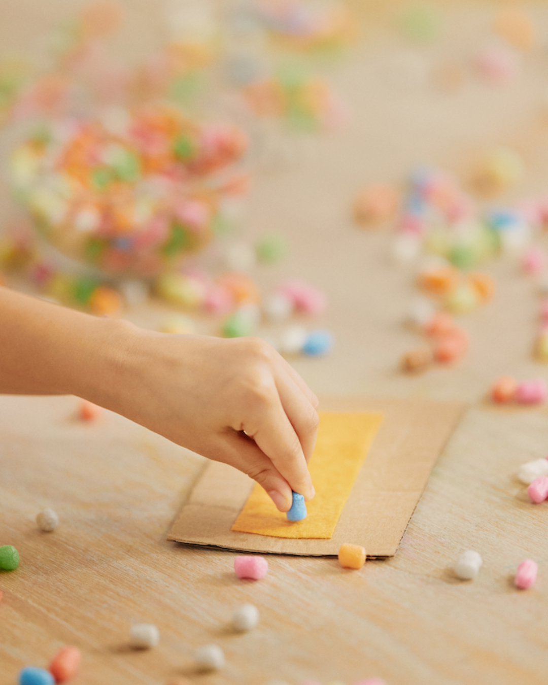 Eine Hand arrangiert blaue Nubsis auf einem Karton, umgeben von bunten Nubsis.