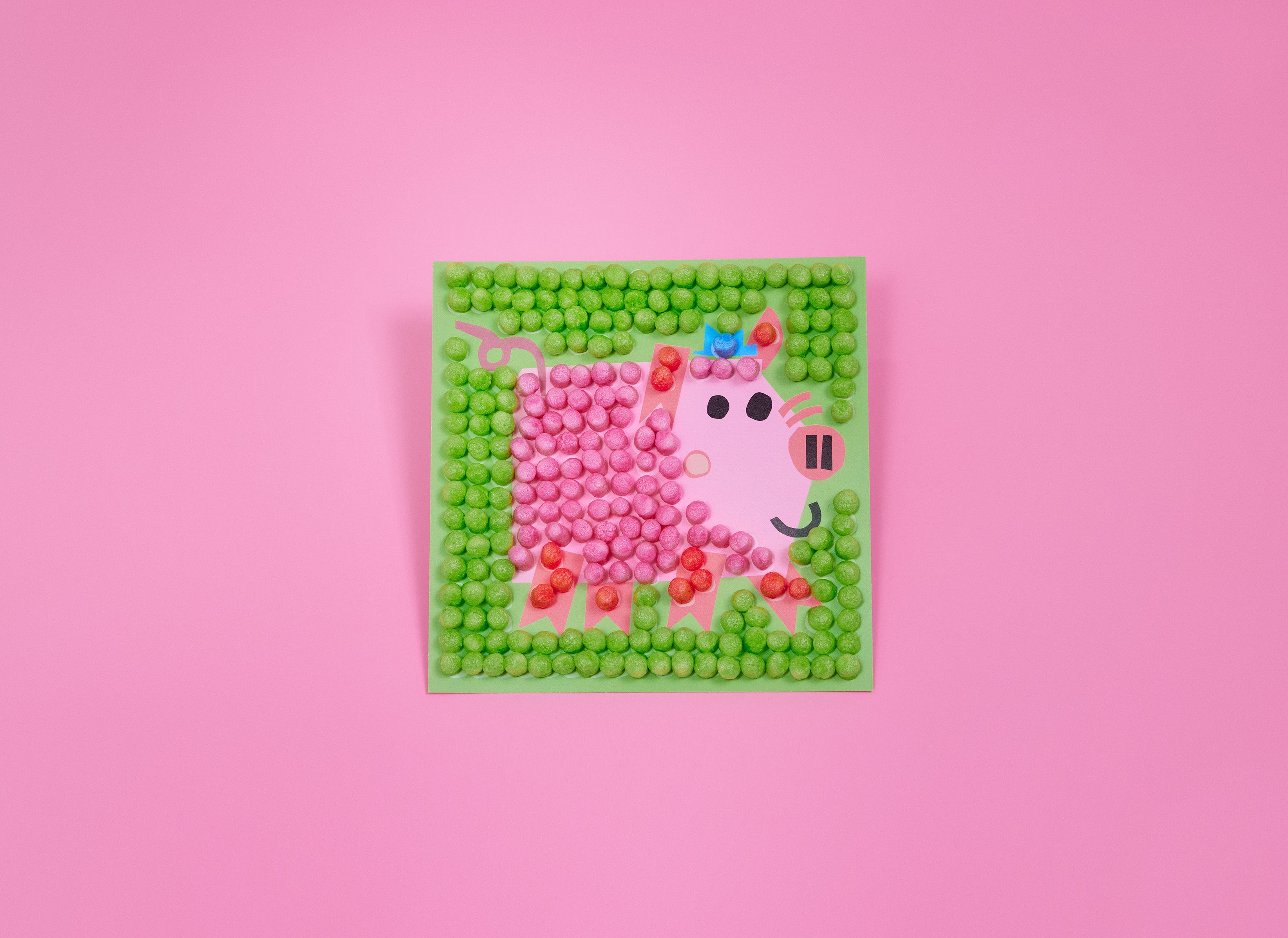 Buntes Bild aus Nubsis zeigt eine rosa Kuh mit blauen Hörnern auf grünem Hintergrund, umgeben von grünen Nubsis, vor pinkem Hintergrund.