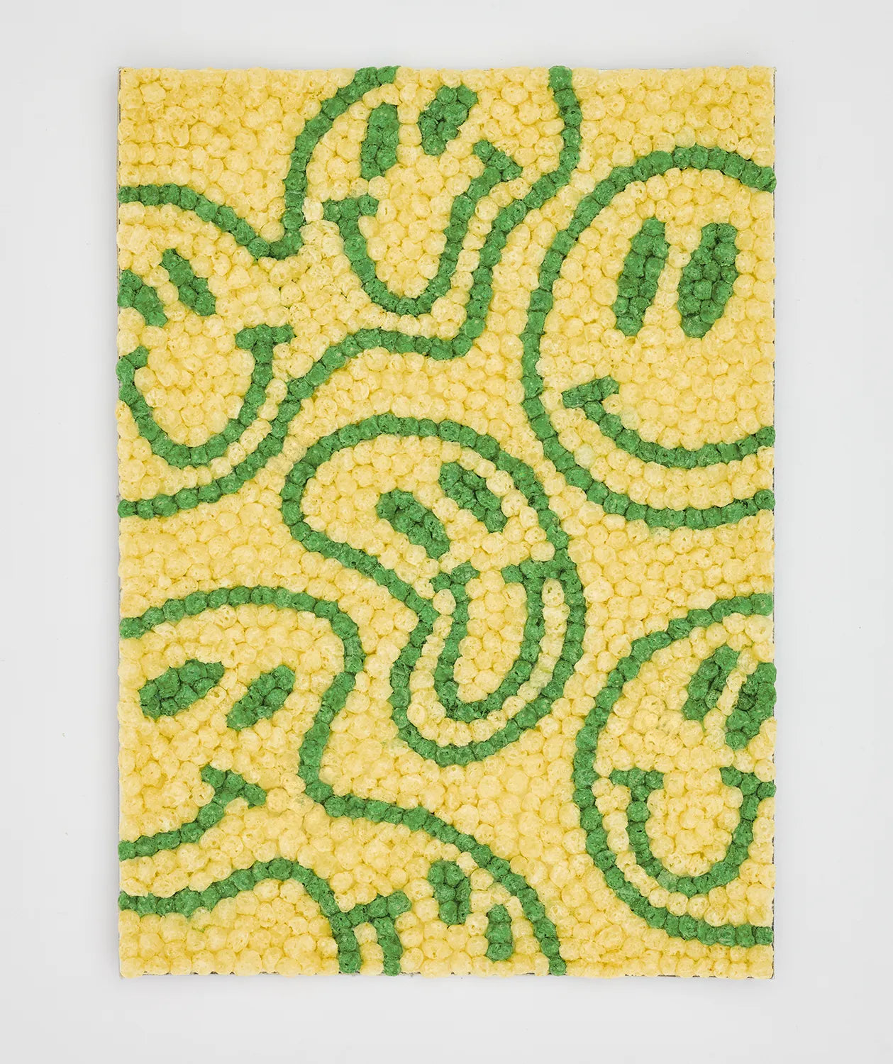 Eine Wand aus gelben und grünen Nubsis bildet lächelnde Gesichter auf hellem Hintergrund.