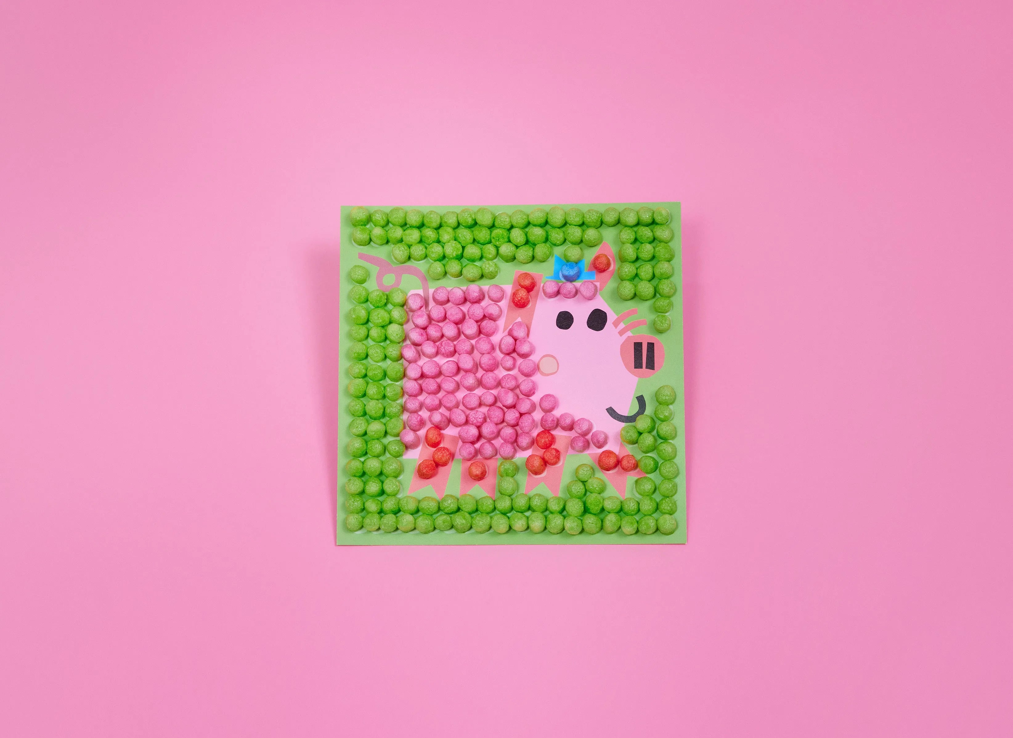 Ein Bild aus bunten Nubsis zeigt ein rosa Schwein mit Hut auf grünem Hintergrund vor rosa Wand.