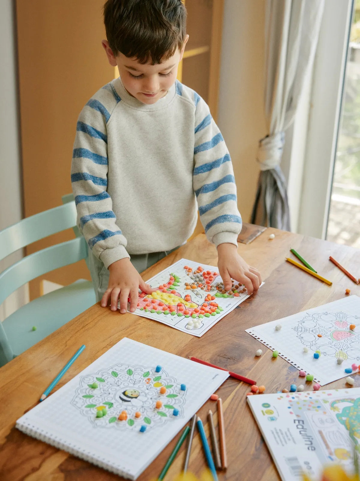 Kind beklebt Motive des Eduline Mosaic Activity Books.