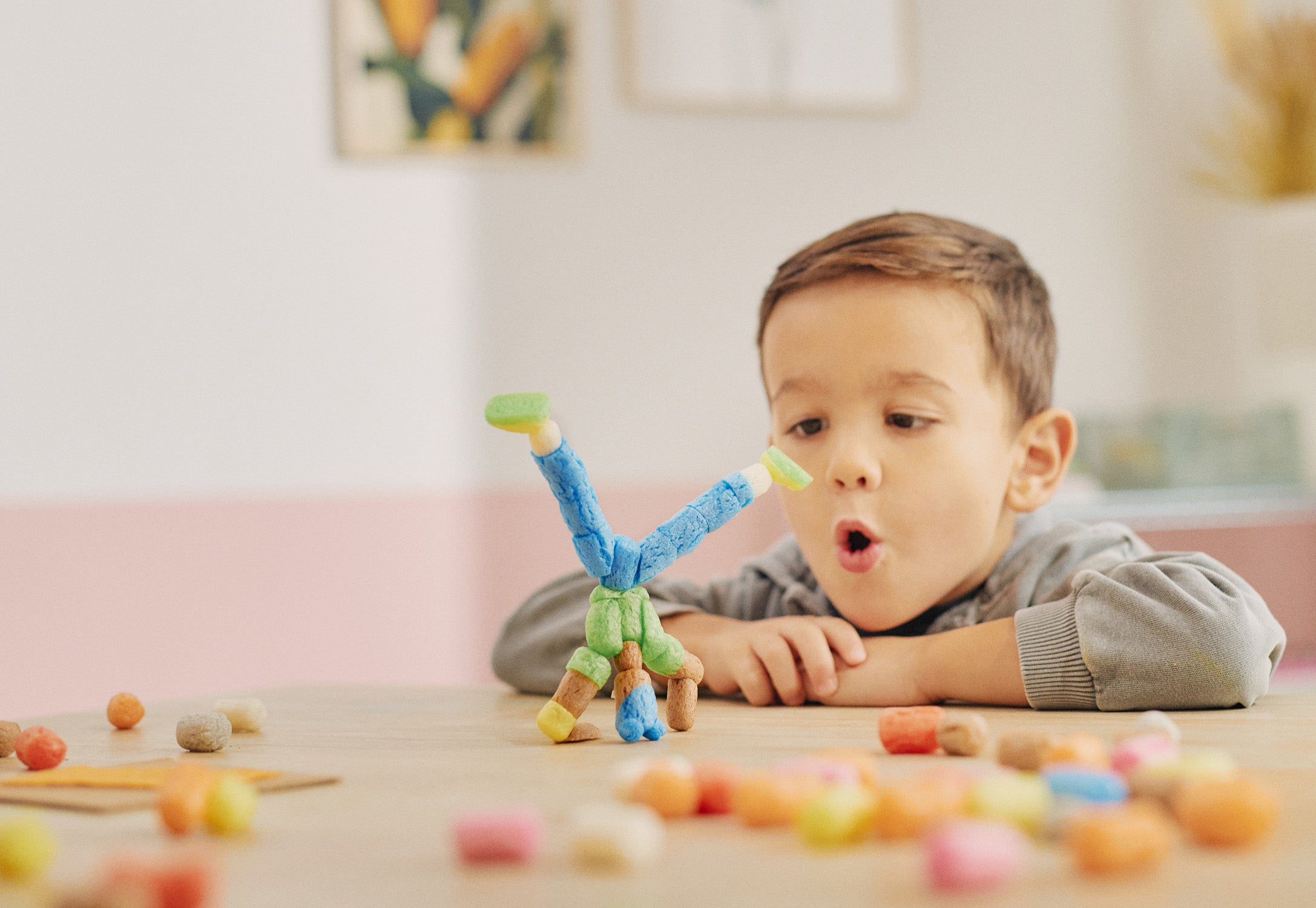 Ein Kind betrachtet fasziniert einen Turm aus bunten Nubsis auf einem Tisch.