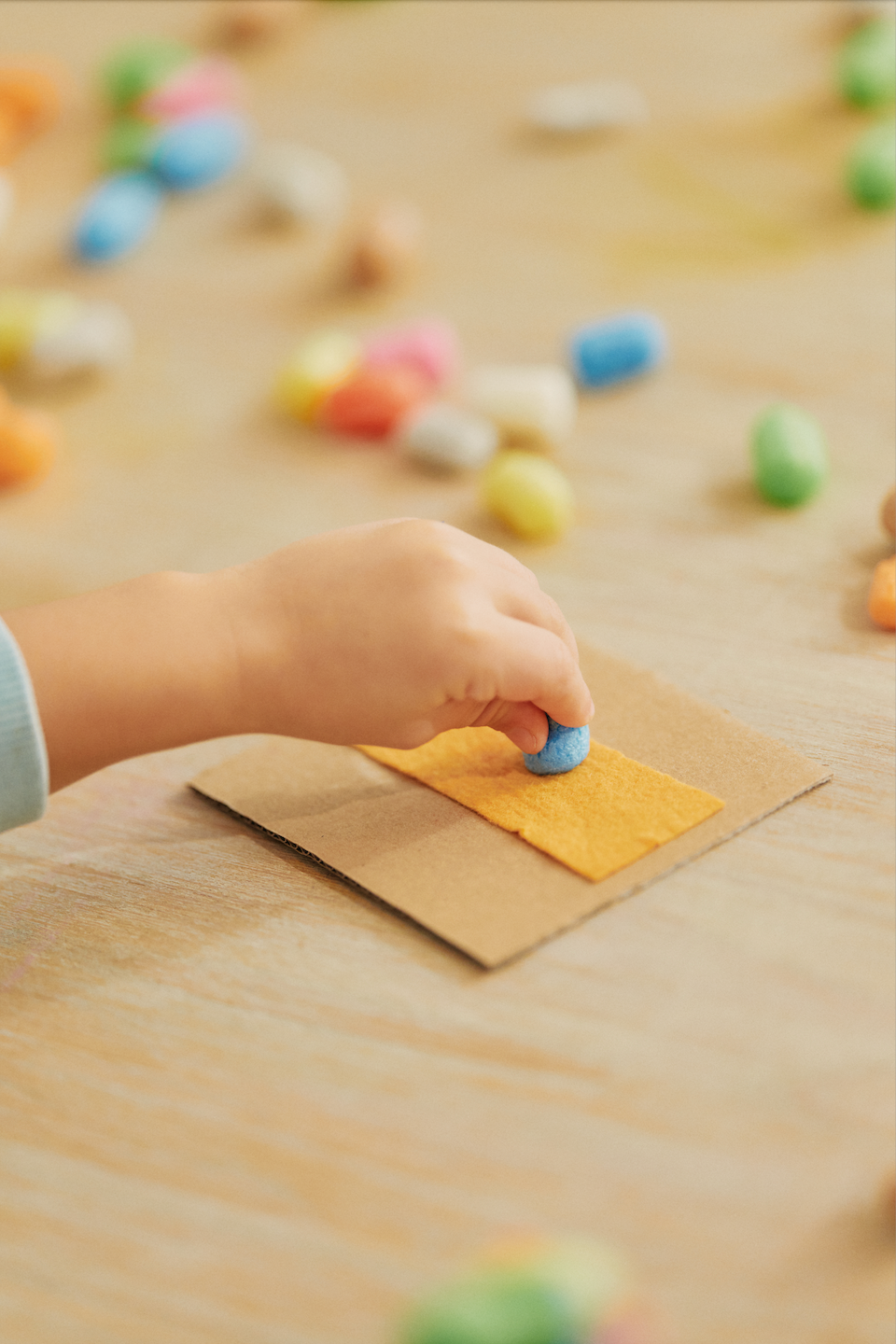 Eine Kinderhand feuchtet ein Playmais-Teil am Schwamm an.