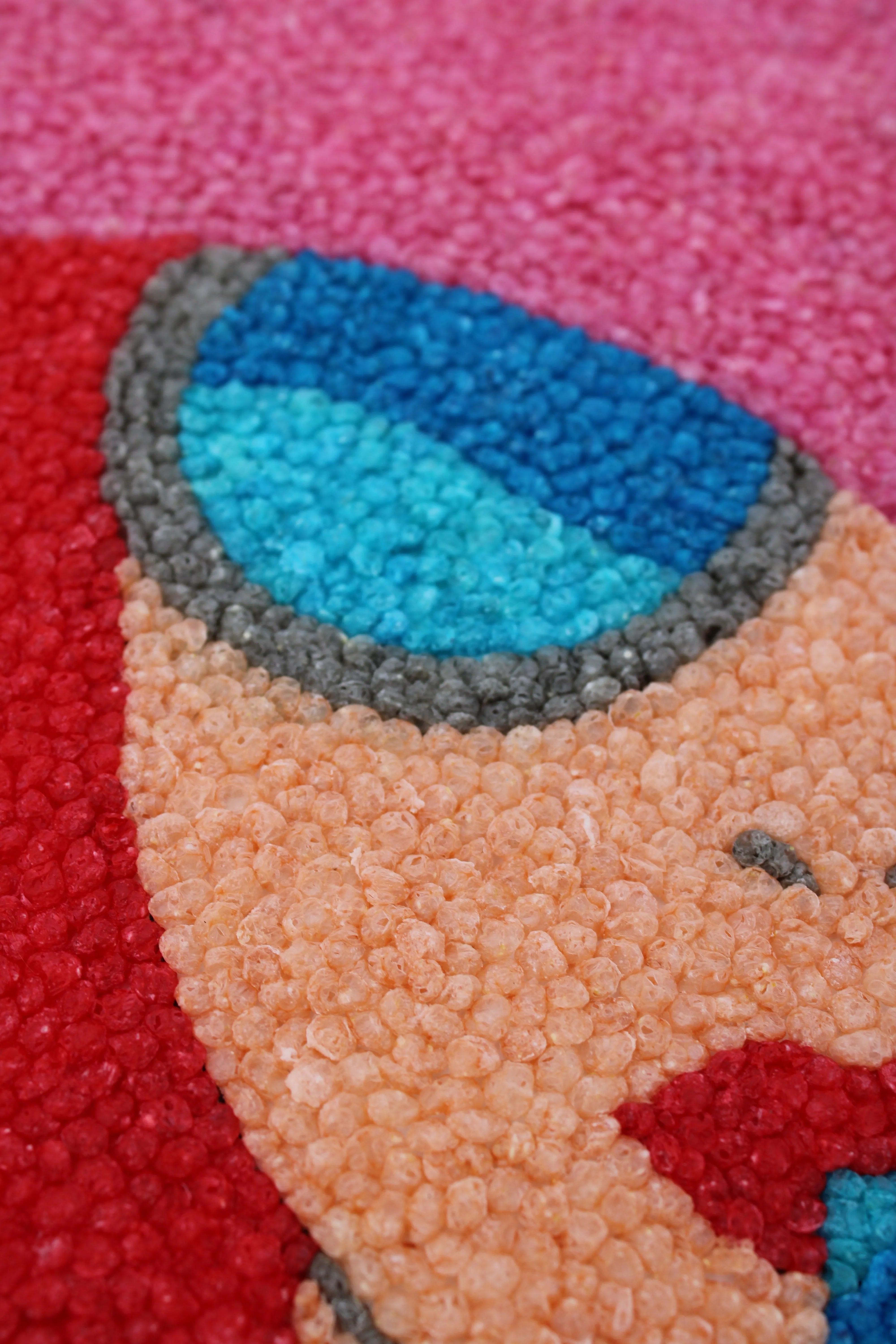 Nahaufnahme von bunten Nubsis in einem geometrischen Muster in Rot, Blau, Rosa, Grau und Beige.