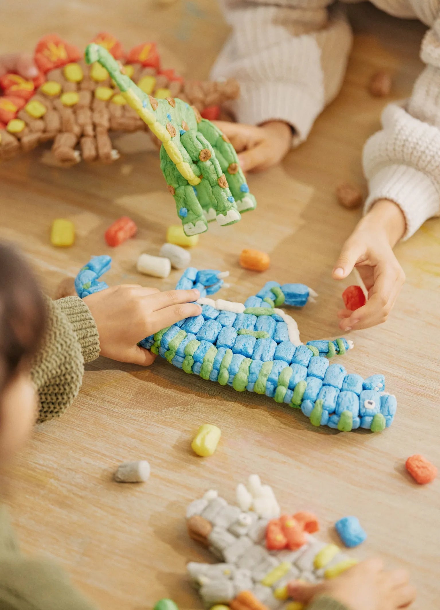 Kinder spielen mit den gebastelten Dinos aus der Playmais Classic Dinoworld. Ein Produkt mit Vorlagen zum Basteln von vier Dinosauriern.