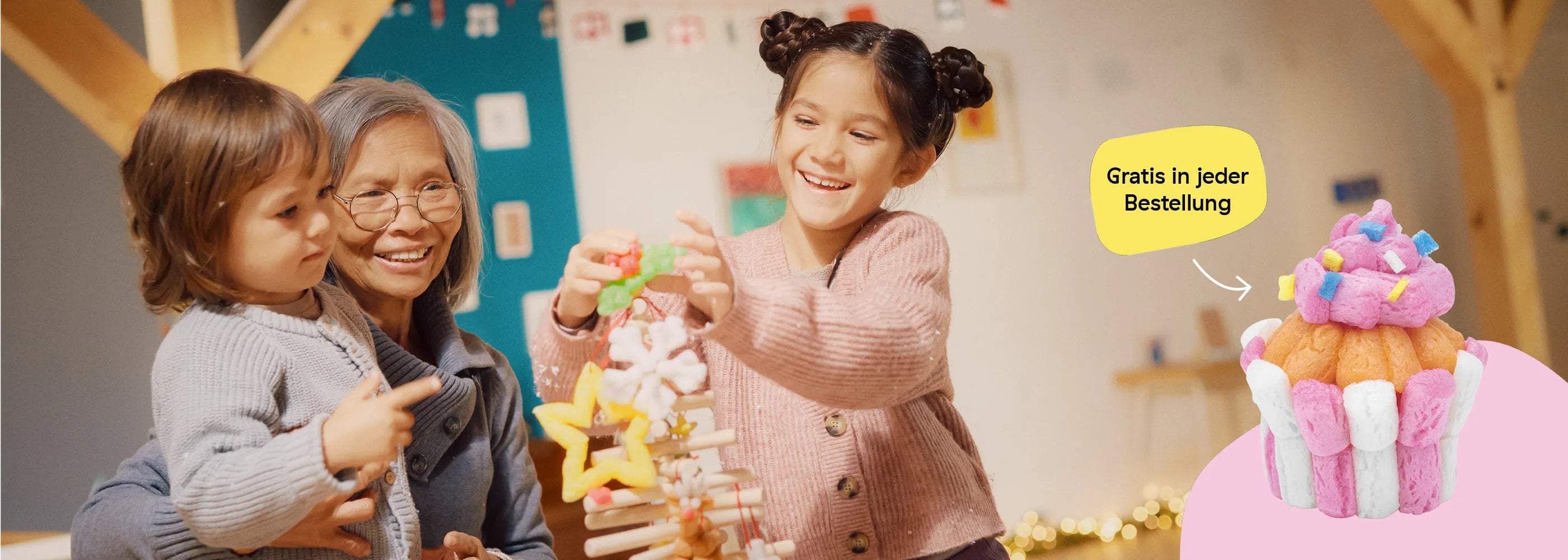 Oma und Kinder schmücken den Weihnachtsbaum. Playmais Classic Cupcake gibt es jetzt in jeder Bestellung.