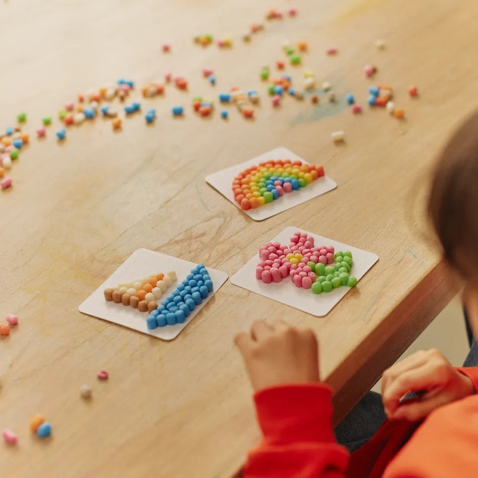 Kind gestaltet bunte Muster mit Nubsis auf einem Tisch.